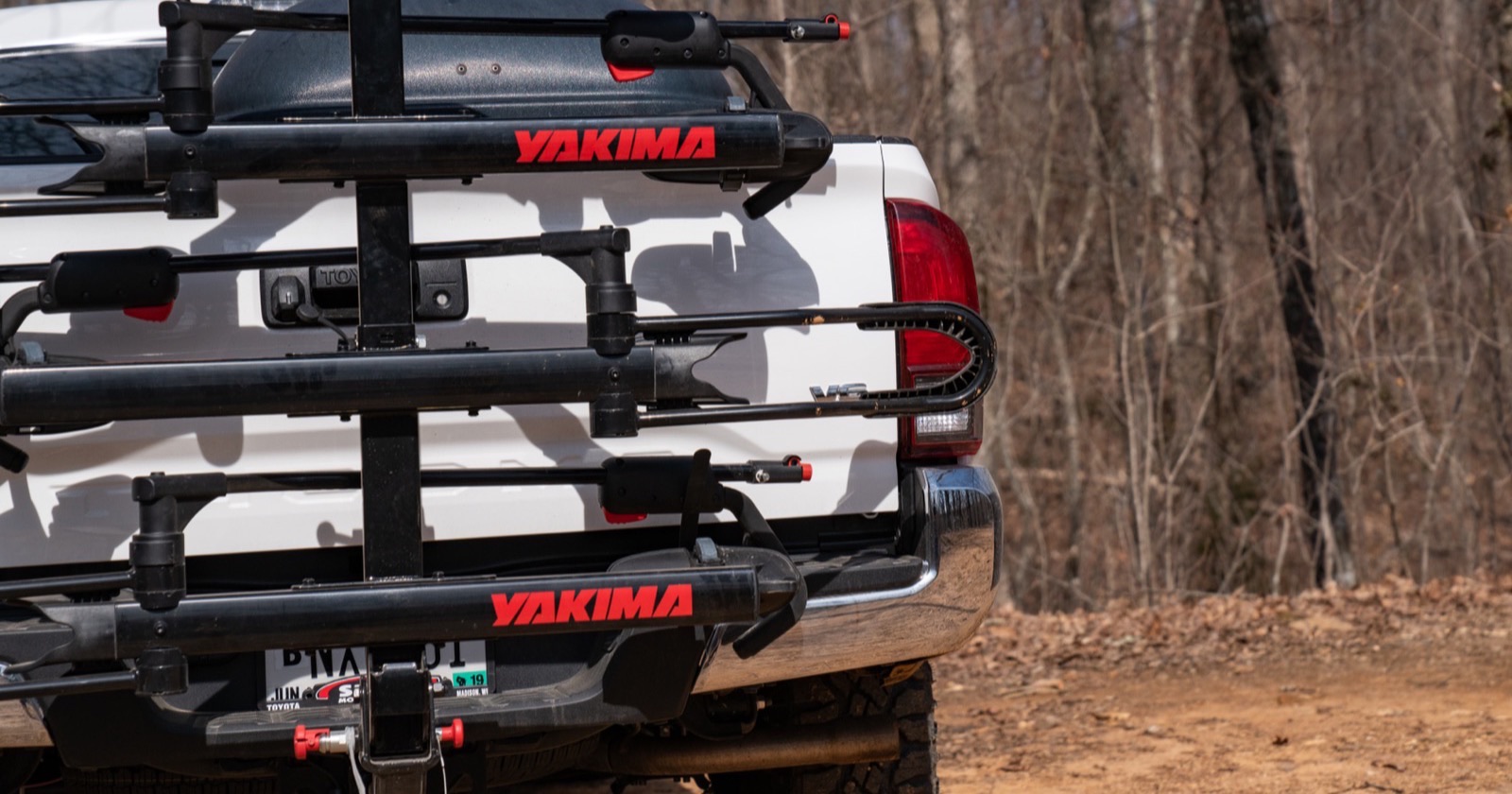 Hitch-mounted Yakima bike rack folded up against the tailgate of a white pickup truck