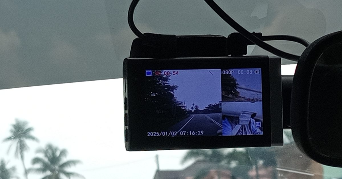 Dashcam mounted at the top of a car windshield, its screen showing a live dual-camera recording view