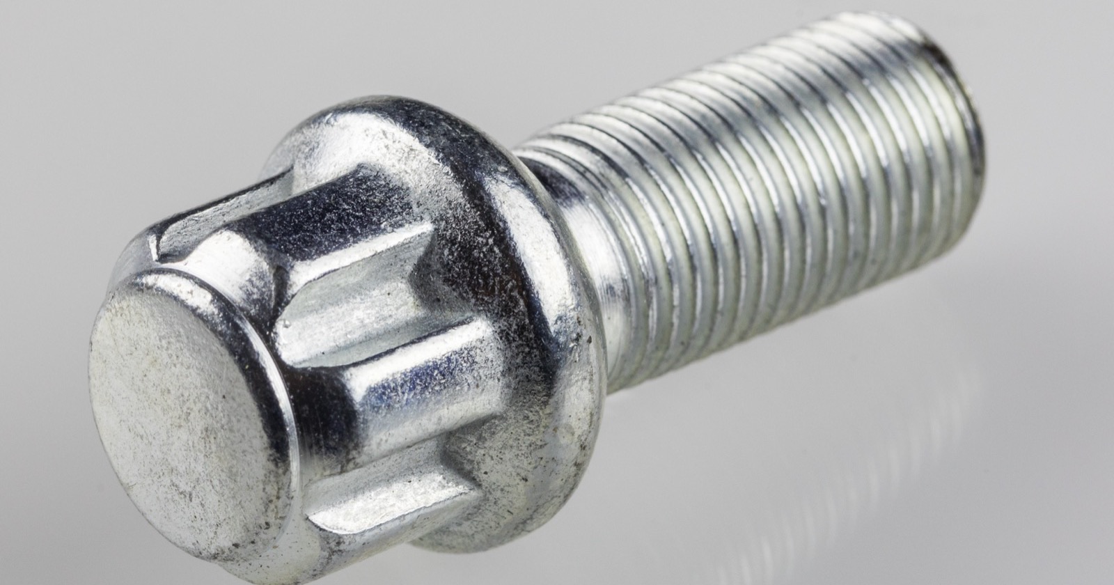 Close-up of a zinc-plated ball-seat wheel lock bolt with a star-pattern head and M14x1.5 thread