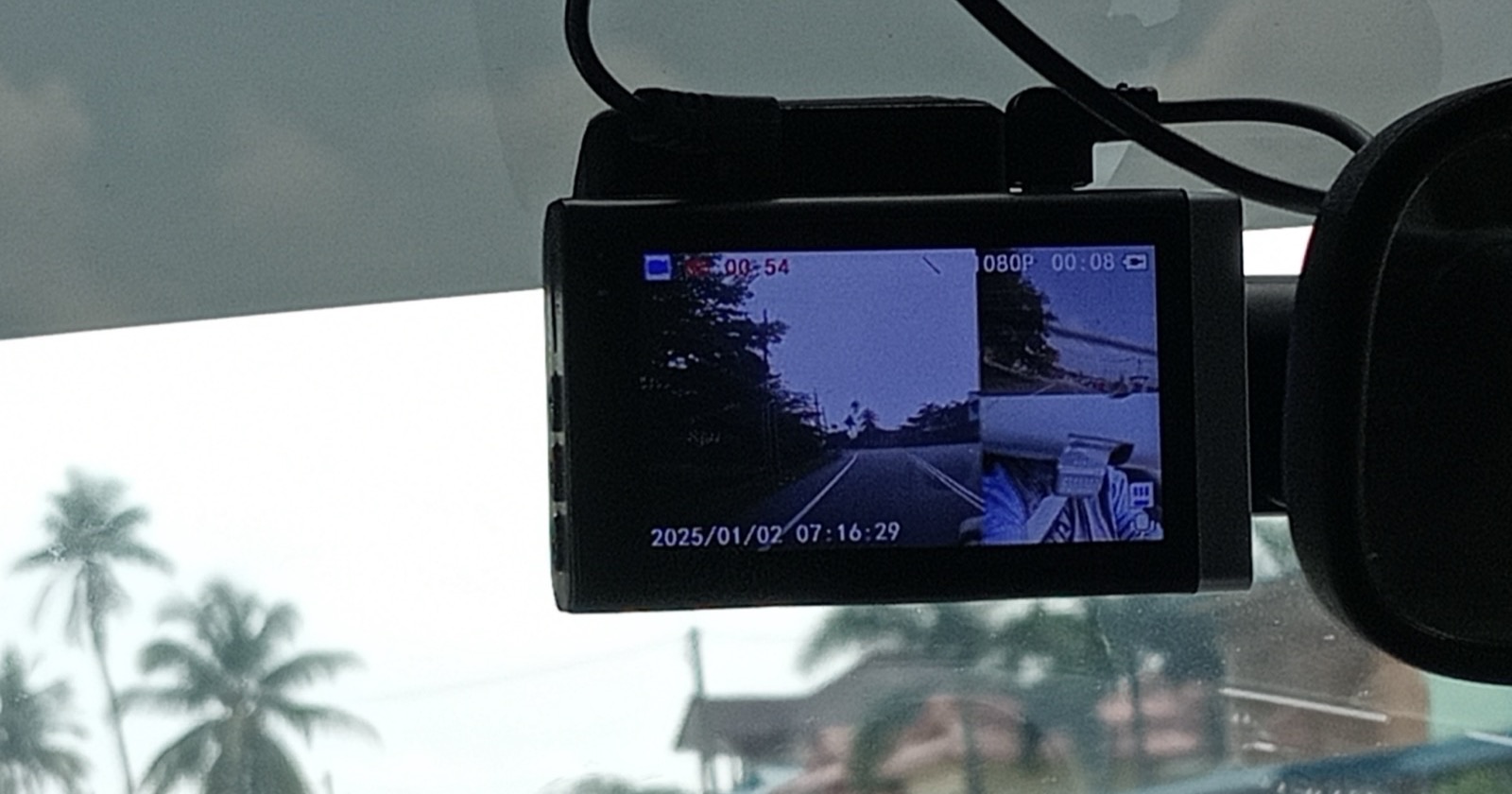 Dual-channel dash cam mounted behind a windshield with its screen showing a split front and second-camera feed
